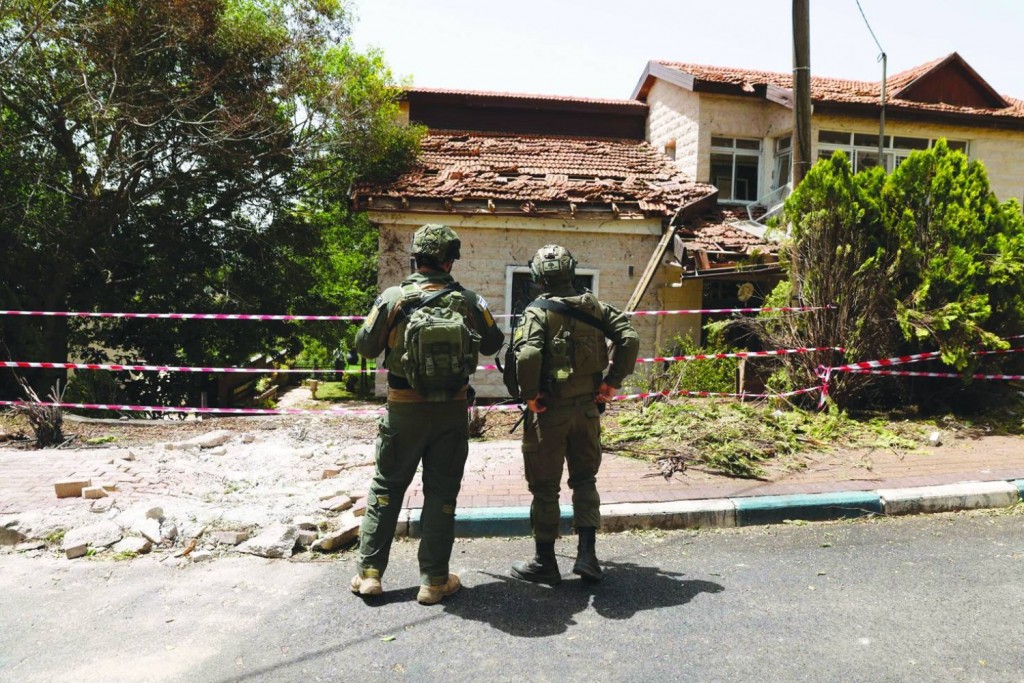 جنديان اسرائيليان يعاينان الأاضرار التي أصابت أحد المنازل في مستعمرة دوفيف جراء صواريخ المقاومة الإسلامية - 27-05-2024